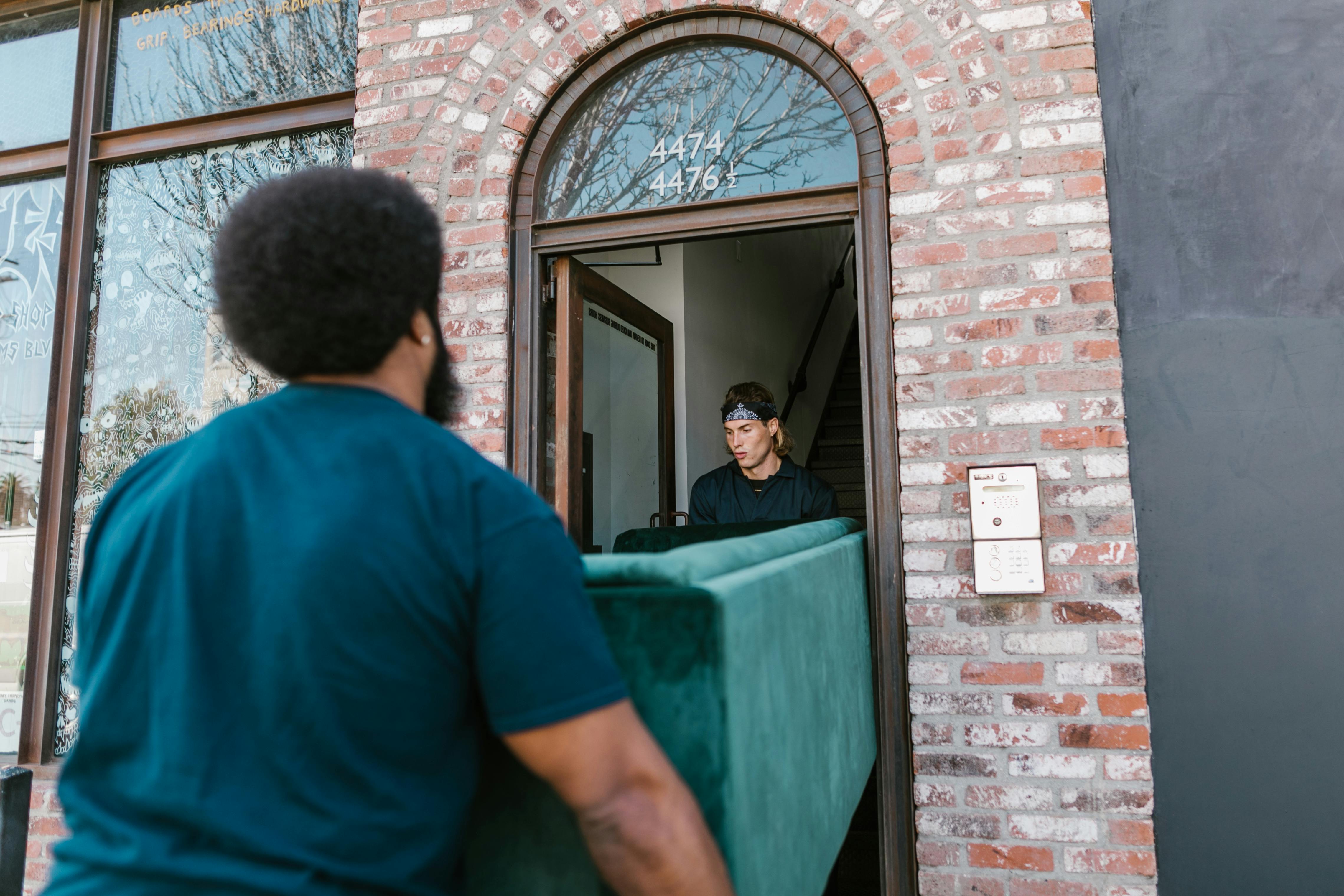 Men Carrying Green Couch while Getting in the House